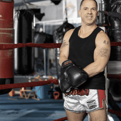 A man performing exercise in front of a boxing ring.