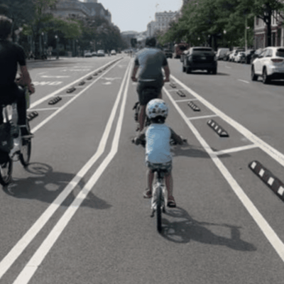 A group of people riding bikes on a city street with bike lanes.