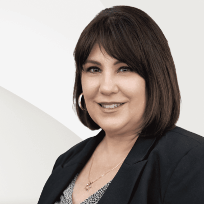 A woman in a business suit is smiling.