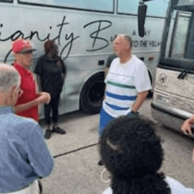 A group of homeless individuals standing in front of a bus in Rhode Island.