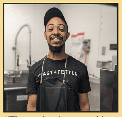 A man with disabilities in an apron standing in front of a kitchen.