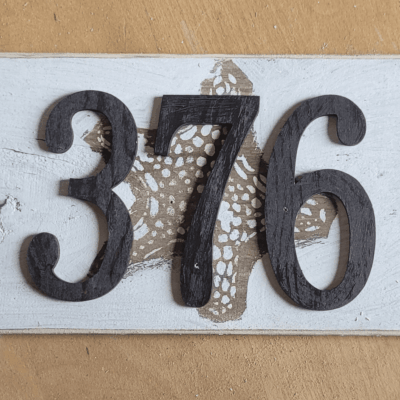 A wooden sign with the number 376 on it, showcasing an artistic touch.
