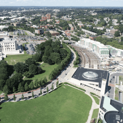 An aerial view of a city with green grass and buildings, including buses in Providence.