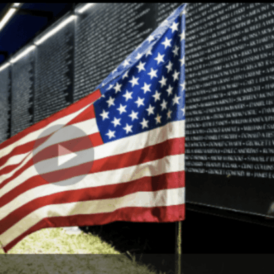 A patriotic american flag is flying in front of the solemn vietnam war memorial, paying tribute to the brave veterans.