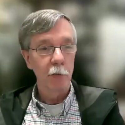 A homeless man with glasses and a mustache is talking.