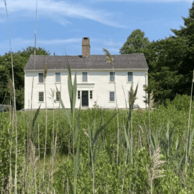 A white house in the middle of tall grass, known as Smith's Castle.