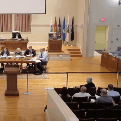A city council sitting at a table in a large room.
