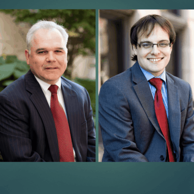 Two lawyers in suits are posing for a photo.