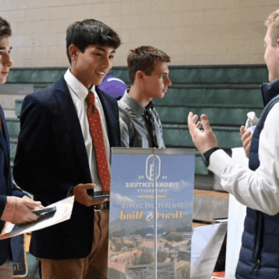 A group of Bishop Hendricken young men talking to each other at a job fair.