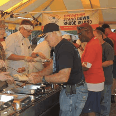 A group of veterans standing under a tent.