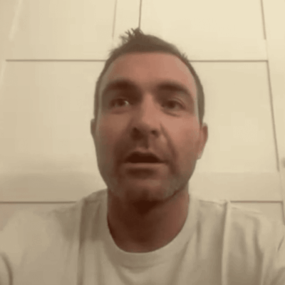 Joe Paolino Jr., wearing a white t-shirt, is looking at the camera.