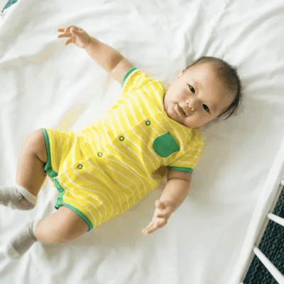 In honor of Baby Safety Month, a precious baby peacefully rests in a yellow striped shirt within the safety of a crib.