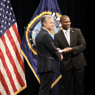Two Central Falls police officers standing in front of an American flag.