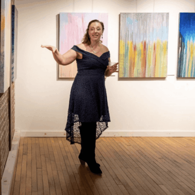 An ART enthusiast standing in front of paintings in an art gallery.