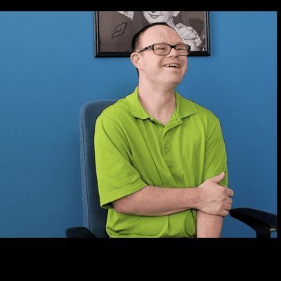 A man in a green shirt sitting in front of a blue wall at Trudeau Center.