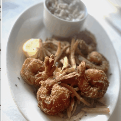 Delicious fried shrimp recipe served on a white plate with a tantalizing dipping sauce.