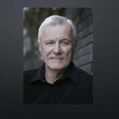 A fetterman smiling in front of a brick wall.