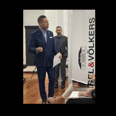 A man in a suit is giving a real estate presentation to a group of people.