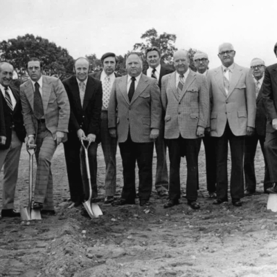 A group of men standing in a fore court with shovels.