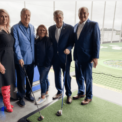 A group of people posing for a picture in front of a TopGolf course.