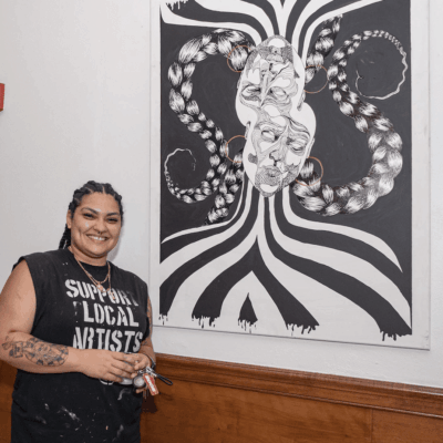 An artist standing in front of a black and white painting.