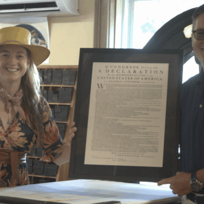 A man and woman standing next to a framed copy of the declaration of independence at BankNewport.