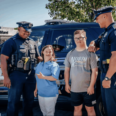 A group of people standing in front of a police car.