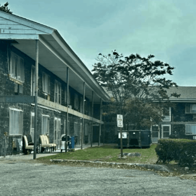 An apartment building in Rhode Island with a parking lot in the background.