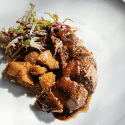 A white plate with a mouthwatering assortment of meat and vegetables, perfect for tantalizing recipe ideas.