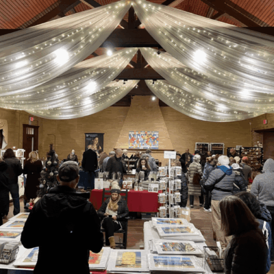 A group of people standing in Linden Place, a room full of books.