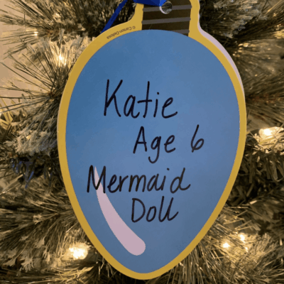 A mermaid doll ornament hanging on a christmas tree for bankRI holiday giving.