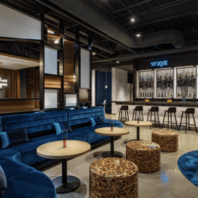The bar area of a hotel with blue couches and a chandelier, perfect for networking.