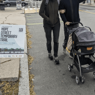 A man and woman stroll down Hope Street, their laughter filling the air as they push a stroller along the sidewalks.