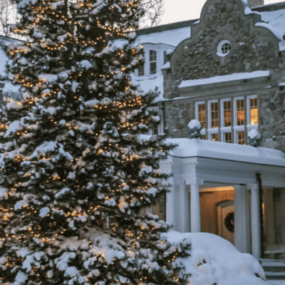 A Blithewold christmas tree covered in snow, displayed beautifully in front of a house.