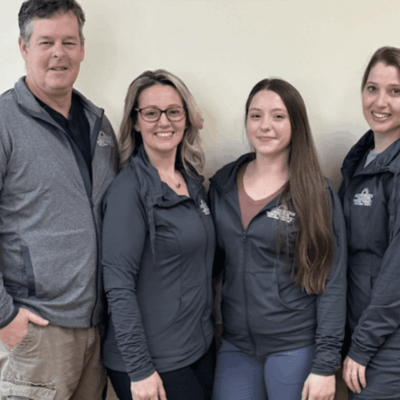 Four people with Parkinson's in gray jackets posing for a photo.