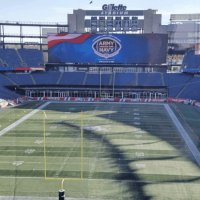 An image of a football field during the Army Navy Game with a large screen.