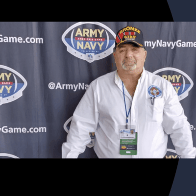 A man standing in front of an army navy banner at the iconic army navy game.