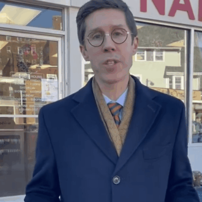 A man in a coat and tie standing in front of a store.