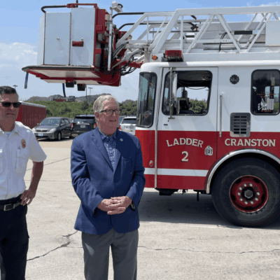 The Cranston fire chief and another man are seen standing in front of a fire truck.