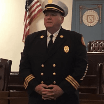 A man in a firefighter uniform standing in a courtroom.