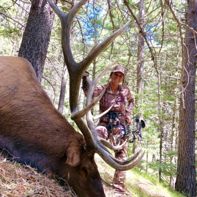 A hunter posing next to a large elk.