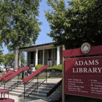 A sign for Adams Library, in Portuguese, in front of a building.
