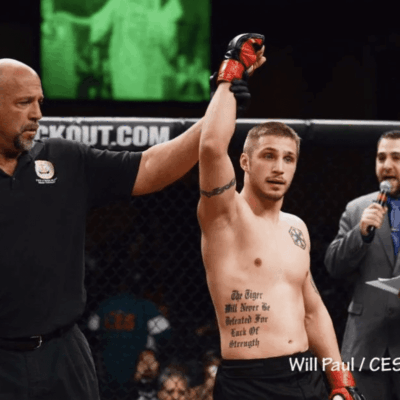 A man with a tattoo on his arm is being congratulated by a referee.
