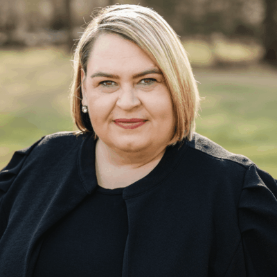 A woman in a black jacket, representing the RI Hospitality Association, standing in a field.