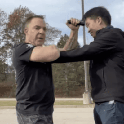 Two men in a parking lot exercise fighting each other.