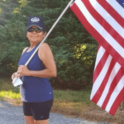 A woman holding an american flag on a road to honor veterans.