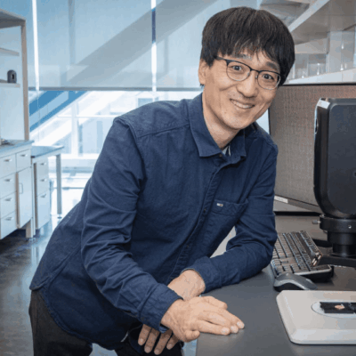 Smiling scientist at his lab microscope.