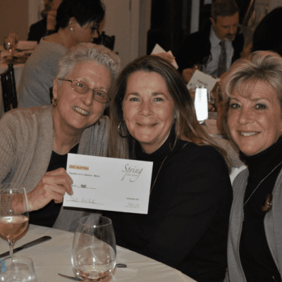 Three women at a charity auction.