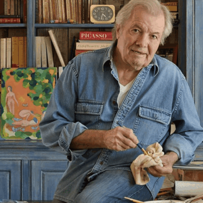 Here's an alt tag for the image: Elderly artist cleaning paintbrush in studio.