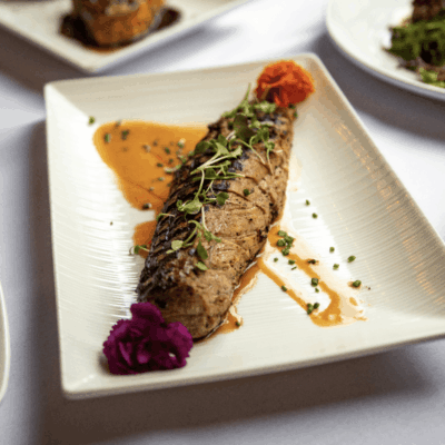 Grilled pork tenderloin with sauce garnish.